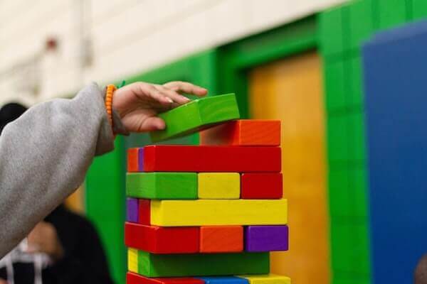 A kid's hand placing a color block on top of other blocks.